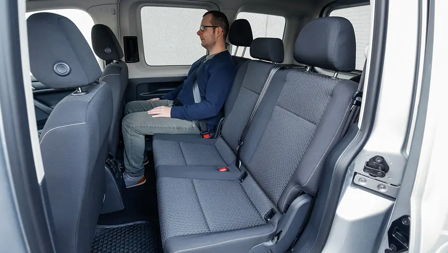 Ein Mann sitzt im Fond des VW Caddy (2015).