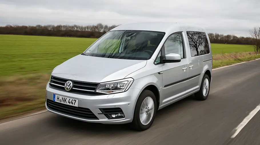 Der VW Caddy (2015) fährt auf einer Landstraße, von vorne links fotografiert.