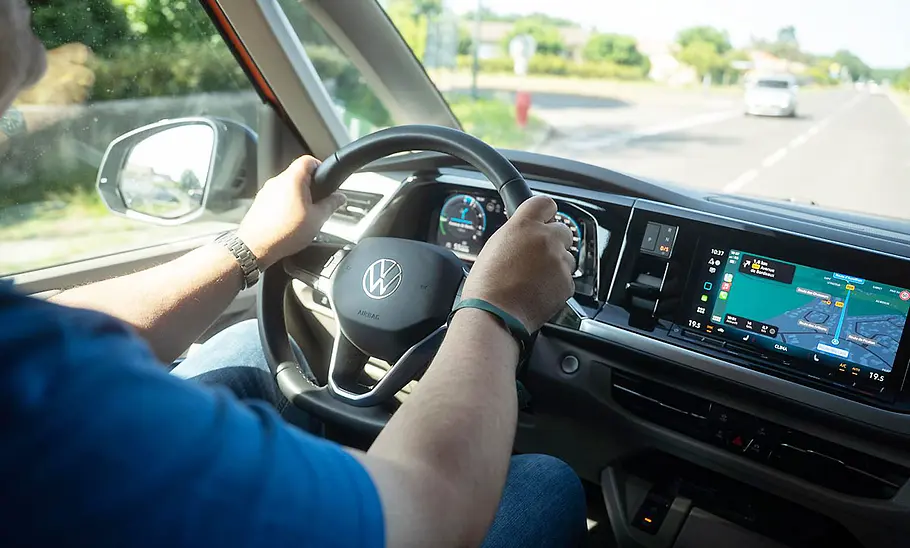 VW California 1.5 eHybrid 4Motion (2025) Die Innenaufnahme zeigt einen Tester am Steuer des VW California 1.5 eHybrid 4Motion (2025).