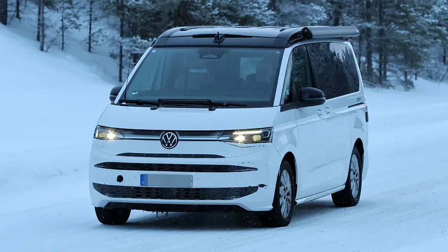 Ein Erlkönig des VW California Facelift auf einer Erprobungsfahrt in Nordschweden auf verschneiter Straße von schräg vorne links.