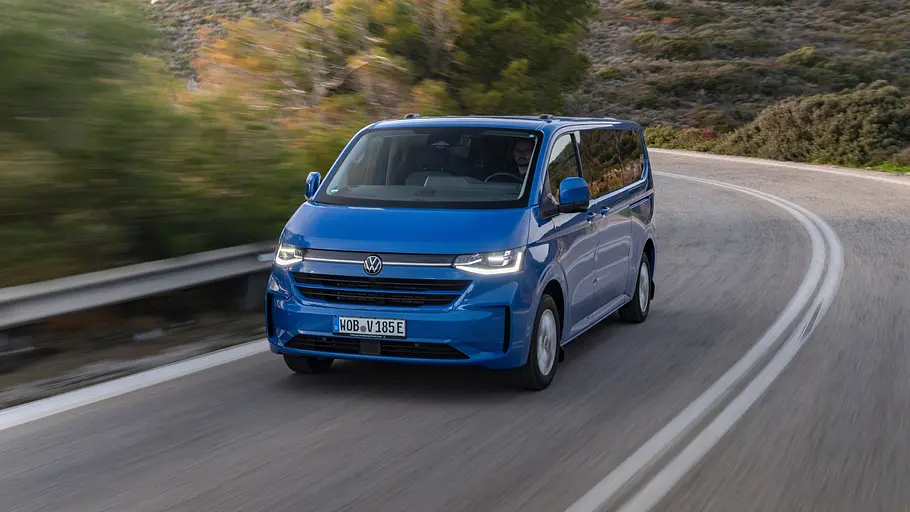 VW e-Caravelle Der VW e-Caravelle fährt auf einer Straße. Ansicht des Fahrzeugs von vorne links.