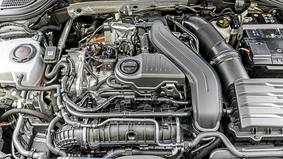 Der Motor des VW Golf kommt ohne eine Plastikabdeckung aus und zeigt viele Leitungen.