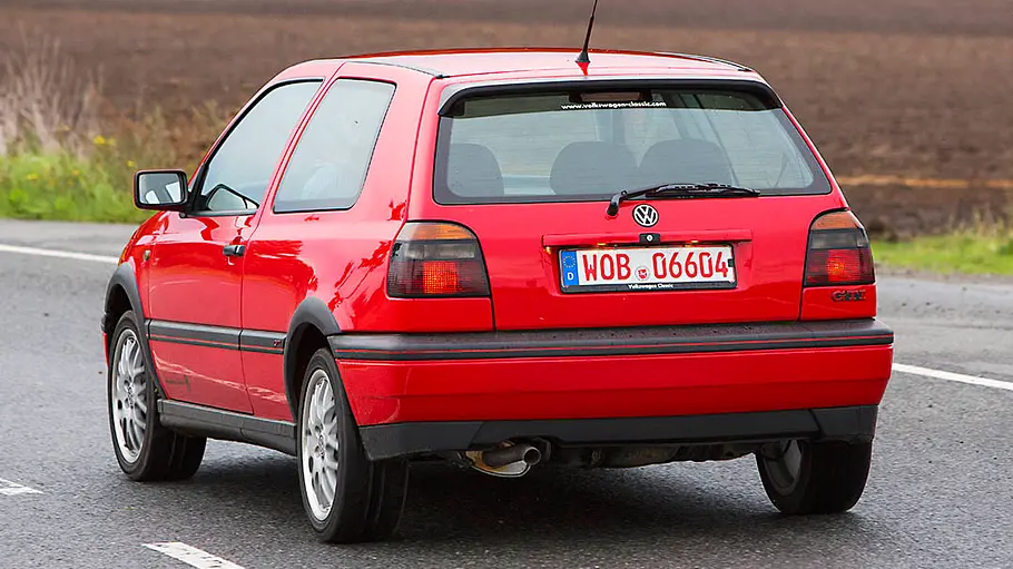 Der VW Golf 3 GTI 20 Jahre GTI fahrend von schräg hinten fotografiert.