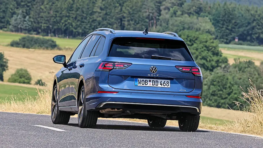 Der VW Golf Variant durch eine Linkskurve fahrend von schräg hinten links fotografiert.