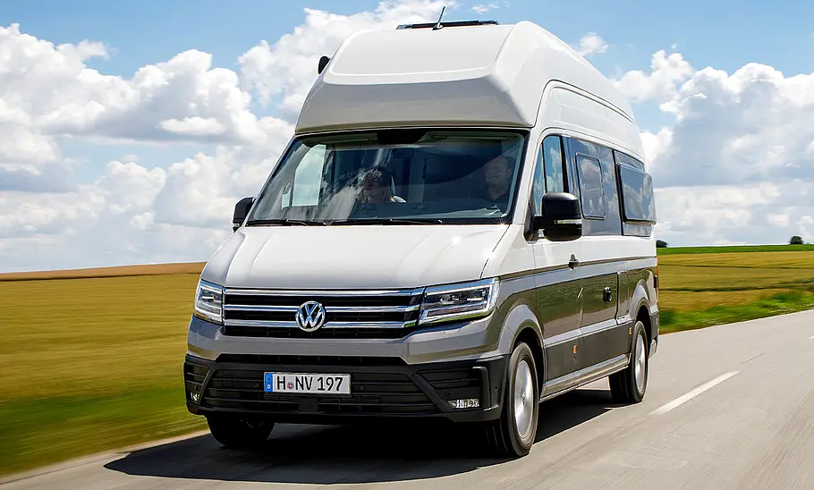 VW Grand California (2018) Der VW Grand California (2018) fahrend auf der Landstraße, von schräg vorne fotografiert.