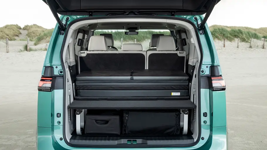 VW ID. Buzz mit Gute-Nacht-Paket Blick durch die geöffnete Heckklappe des VW ID. Buzz mit Gute-Nacht-Paket auf das zusammengefaltete Campingmodul.