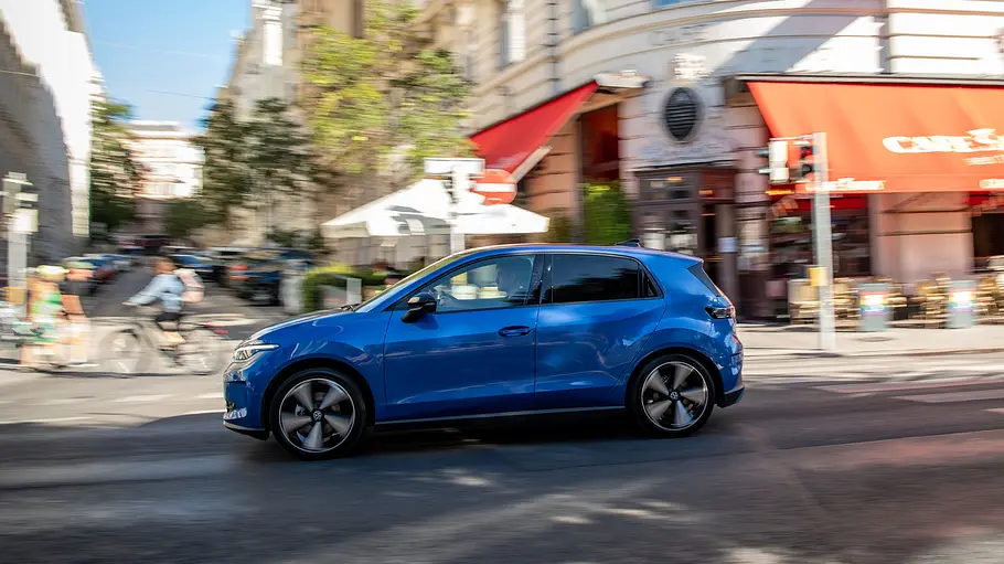 VW ID. Polo Fahrbericht Der VW ID. Polo fahrend von schräg seitlich links vor einer Stadtkulisse.