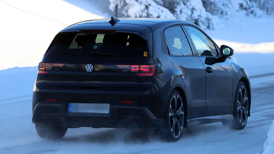 Der VW ID. Polo GTI fährt als Erlkönig auf einer verschneiten Straße, von hinten rechts fotografiert.