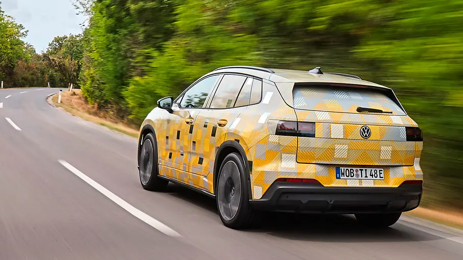 Getarnter Prototyp des VW ID.Tiguan mit gold-blauer Tarnfolie, fahrend von schräg hinten