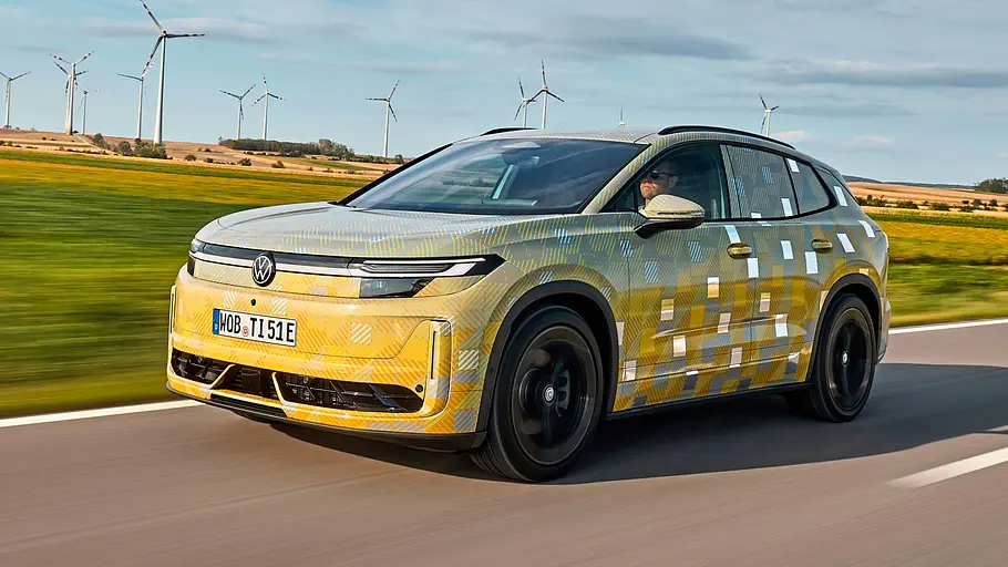 Getarnter Prototyp des VW ID.Tiguan mit gold-blauer Tarnfolie, fahrend von schräg vorn
