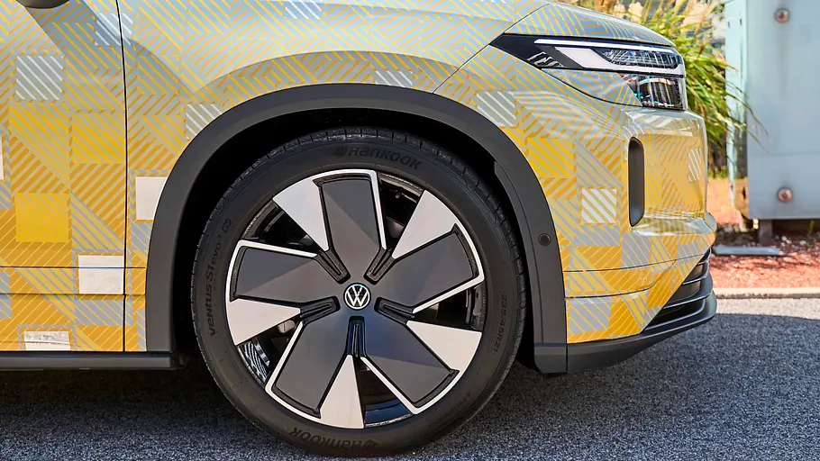 Getarnter Prototyp des VW ID.Tiguan mit gold-blauer Tarnfolie, Vorderrad in Nahaufnahme