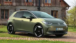 Der VW ID.3 statisch von schräg vorne links vor einem alten Bauernhaus auf einem gepflasterten Weg geparkt. - Foto: VW
