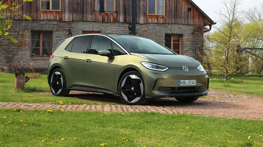 VW ID.3 Der VW ID.3 statisch von schräg vorne links vor einem alten Bauernhaus auf einem gepflasterten Weg geparkt.