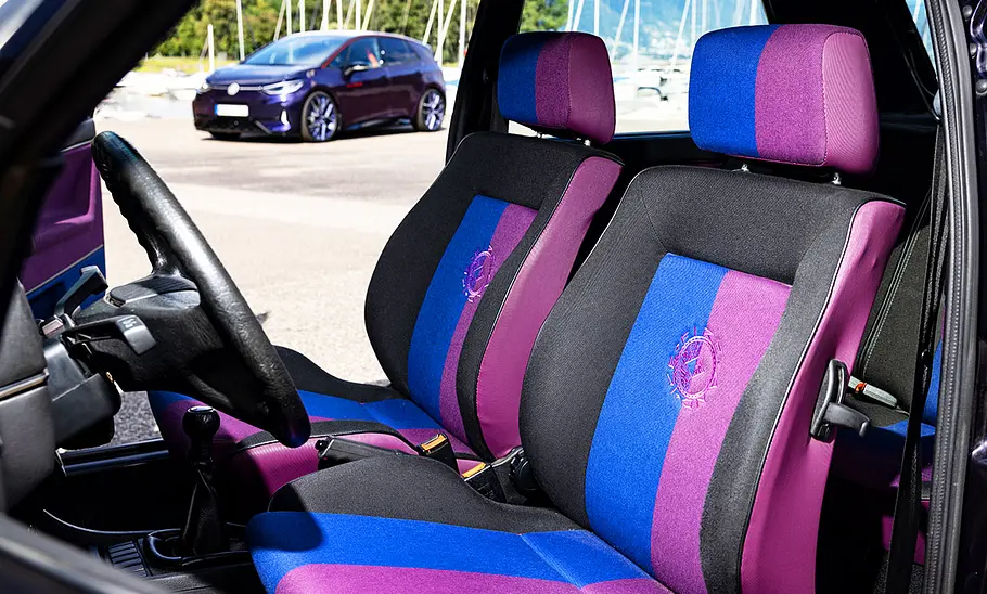 Das Interieur des VW Golf II Fire+Ice – die geöffnete Beifahrertür erlaubt den Blick auf den hinter dem Golf stehenden VW ID.3 GTX Fire+Ice (2025).