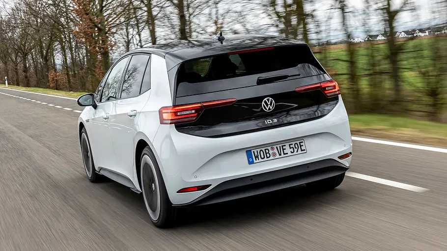 VW ID.3 Der VW ID.3 fährt auf einer Landstraße, von hinten links fotografiert.