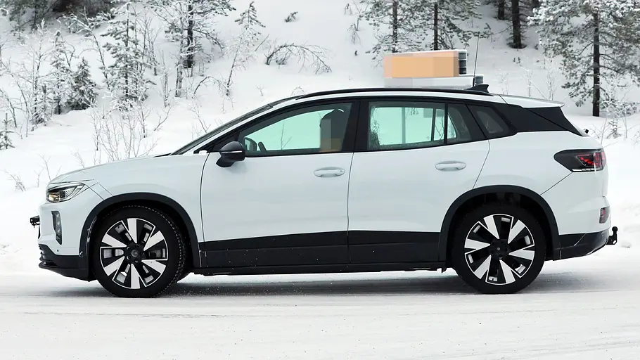 VW ID.4/ID. Tiguan Der VW ID.4 fährt als Erlkönig durch den Schnee, fotografiert von der Seite.