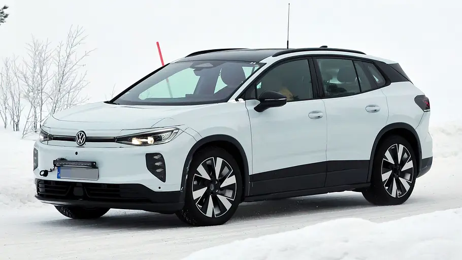 VW ID.4/ID. Tiguan Der VW ID.4 fährt als Erlkönig durch den Schnee, fotografiert von schräg vorne.