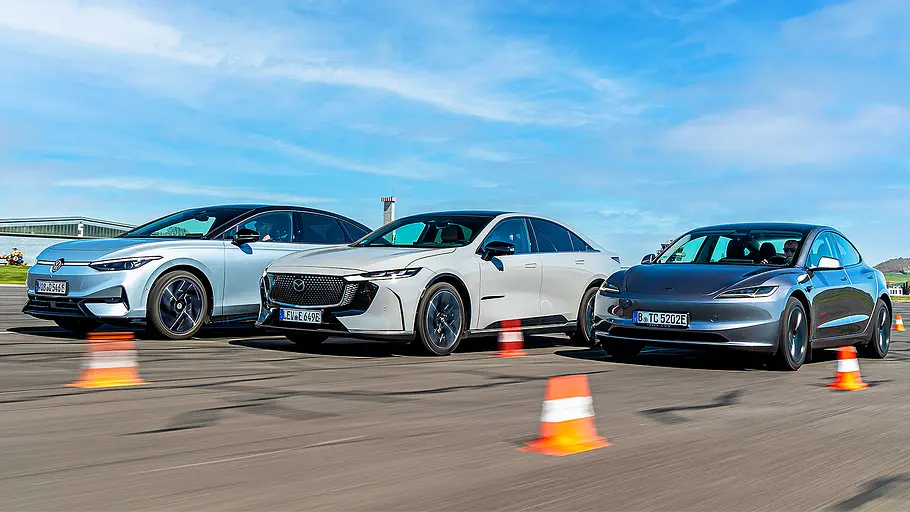 Blick von schräg vorne auf die drei fahrenden Elektro-Limousinen VW ID.7, Mazda6e und Tesla Model 3.