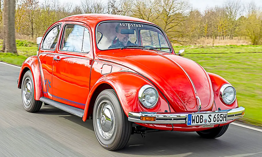 Der fahrende VW Käfer in der Ansicht von schräg vorne.