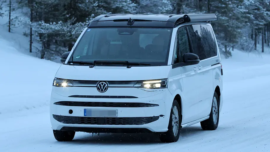 Das VW California Facelift (2026) fährt als Erlkönig auf einer verschneiten Straße, von vorne fotografiert.