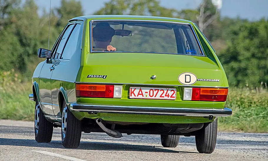 Der VW Passat B1 fährt über eine Landstraße, fotografiert von schräg hinten.
