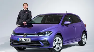 Redakteur Alexander Koch steht im Studio neben dem VW Polo Facelift (2021), von vorne links fotografiert. - Foto: VW