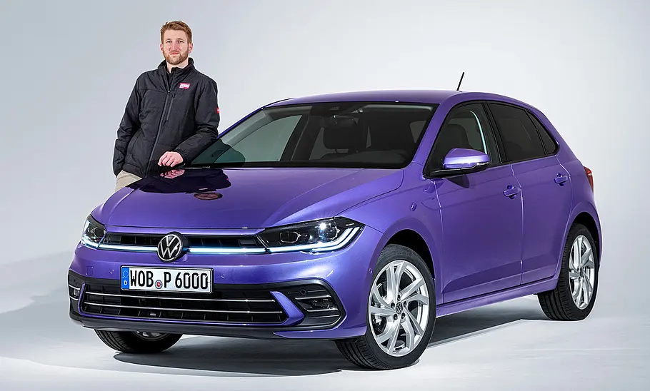 Redakteur Alexander Koch steht im Studio neben dem VW Polo Facelift (2021), von vorne links fotografiert.
