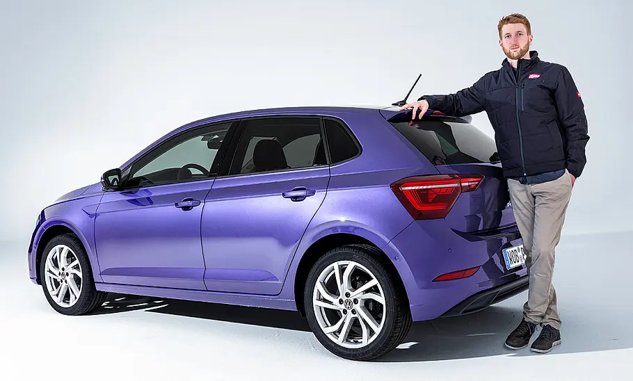 Redakteur Alexander Koch steht im Studio hinter dem VW Polo Facelift (2021), von hinten links fotografiert.