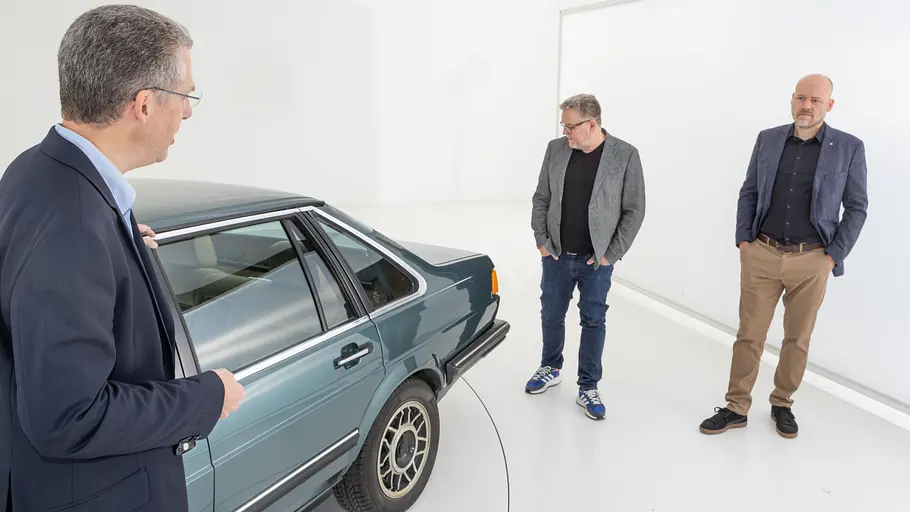 Drei Personen am Heck des VW Santana stehend fotografiert. 