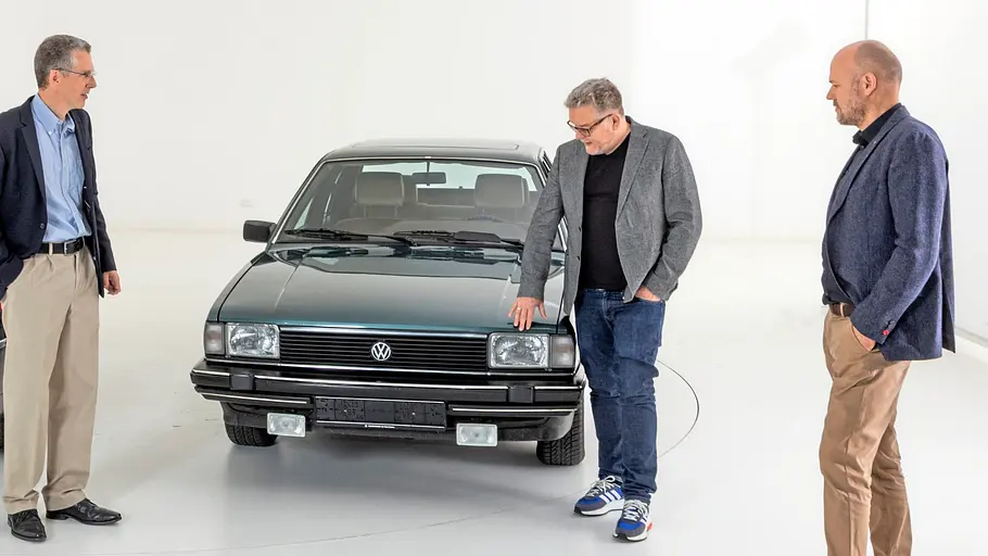 Drei Personen an der Front des VW Santana stehend fotografiert. 