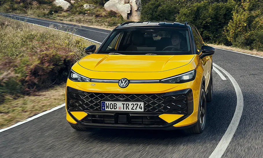 VW T-Roc Der VW T-Roc fährt durch eine Rechtskurve, fotografiert von vorne.