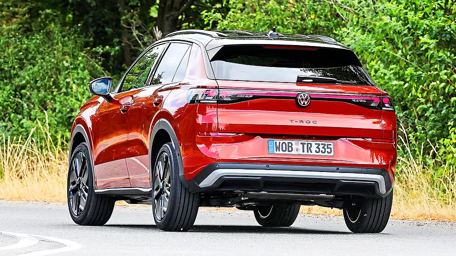 Blick von schräg hinten auf den fahrenden VW T-Roc.