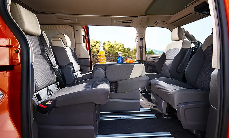 VW California (2024) Die Ansicht durch die Schiebetür des VW California (2024) wirft einen Blick in den Innenraum mit gedrehten Frontsitzen.