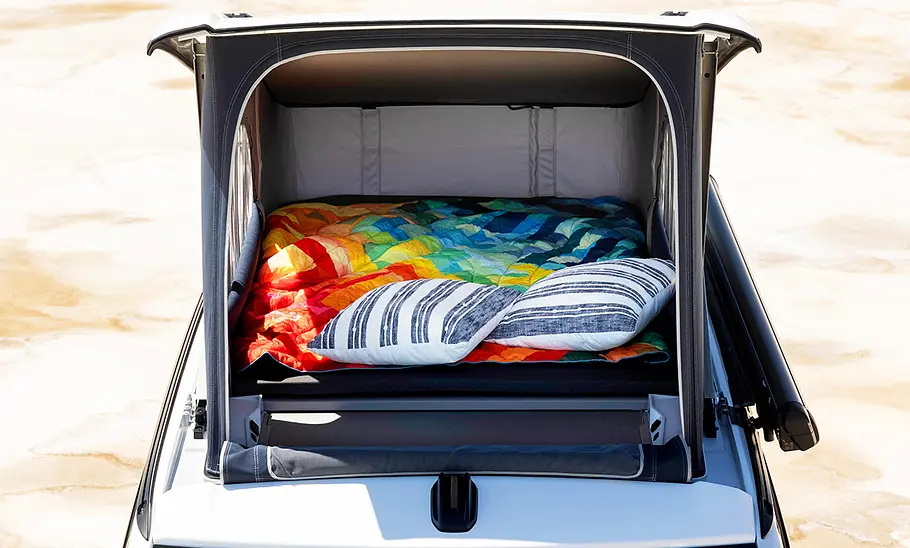 VW California (2024) Das Foto zeigt den Schlafbereich unter dem Aufstelldach des VW California (2024). Ansicht von außen auf das Fliegengitter vorne.