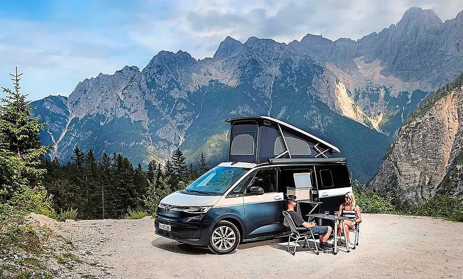 Camping-Reise durch Slowenien im VW T7 California Camping-Reise durch Slowenien im VW T7 California; stehend, Ansicht schräg vorne, Campingmöbel sind aufgebaut, Alpenpanorama