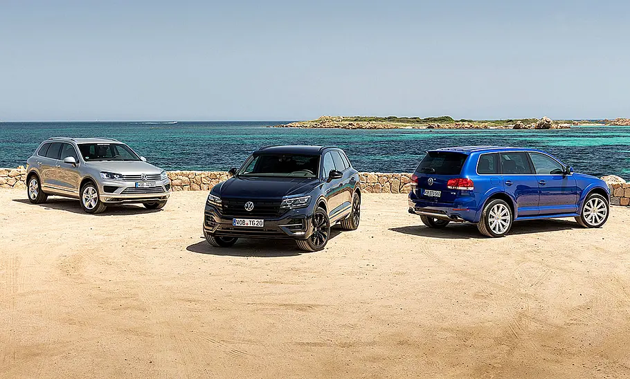 VW Touareg Generationen 1-3 Die Generationen 1-3 des VW Touareg als Gruppenbild: Die zweite Generation von schräg vorne fotografiert links, die Generation drei von schräg vorne in der Mitte und Nummer 2 von schräg hinten fotografiert rechts.