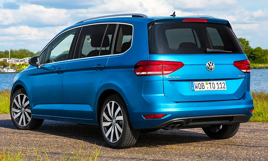 VW Touran (2015) Der VW Touran (2015) steht an einem Gewässer, von hinten links fotografiert.