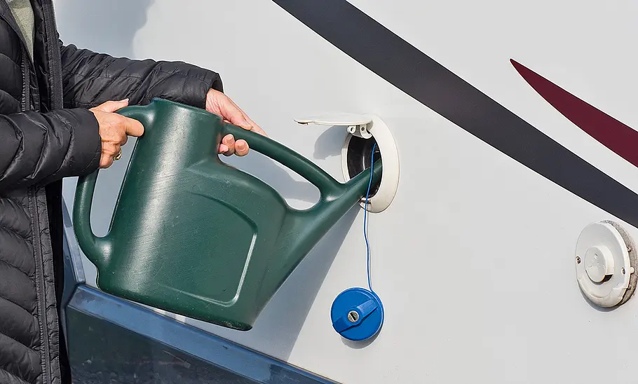 Person füllt Trinkwasser mit Gießkanne in den Tank des Wohnmobils