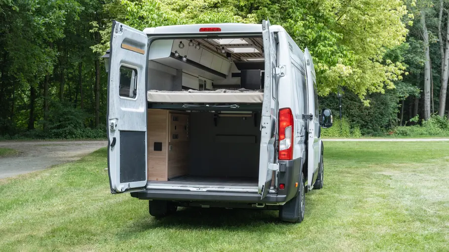 Der Weinsberg Caralife 630 LQ statisch von schräg hinten rechts mit geöffneten Hecktüren auf einer Wiese parkend.