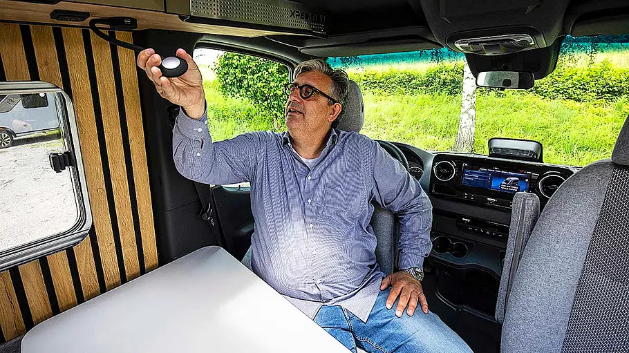 Eine Person sitzt auf dem zur Sitzgruppe gedrehten Fahrersitz des Weinsberg X-Pedition und betätigt eine Schwanenhals-Leselampe.
