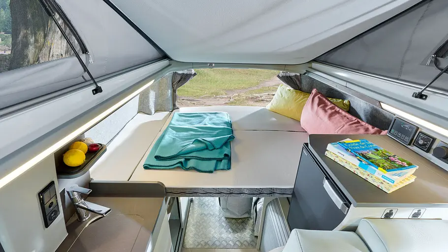 Westfalia Kipling Die Innenaufnahme zeigt das in Schlafpoistion gebrachte Heckbett des Westfalia Kipling bei geöffnetem Aufstelldach.