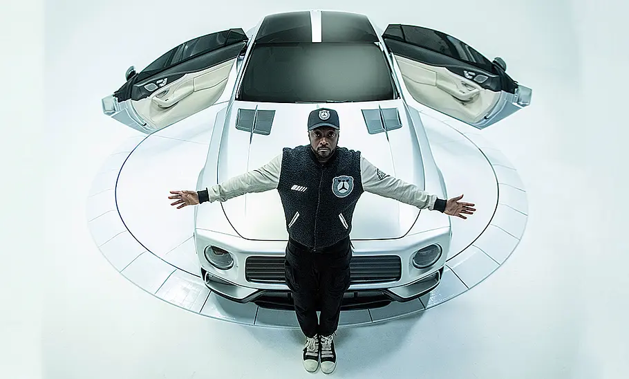 WILL.I.AMG The Flip im Studio mit geöffneten Türen, Ansicht von vorne. Will.I.Am steht mit ausgebreiteten Armen vor dem Fahrzeug.