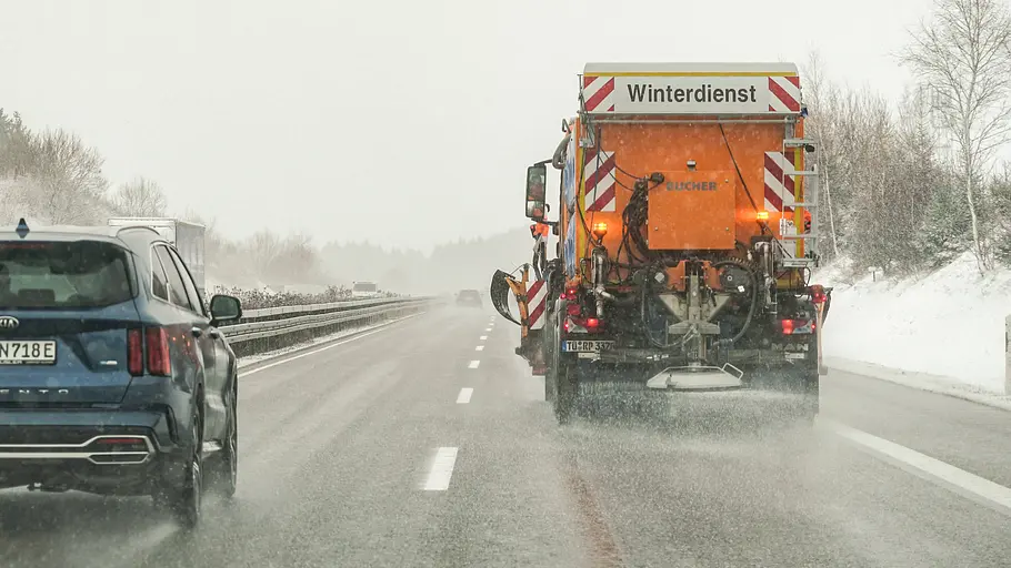 Streufahrzeug des Winterdienstes im Einsatz auf der Autobahn, fotografiert von hinten.
