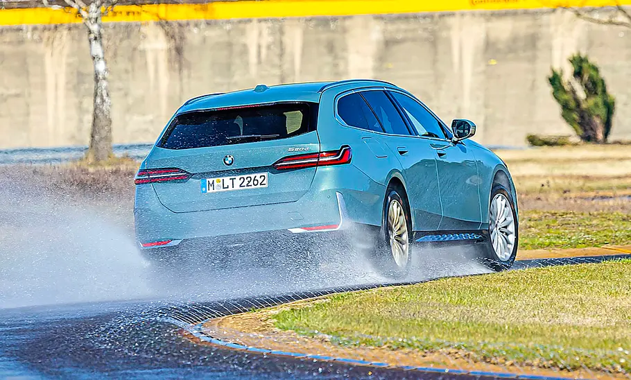 Der BMW 520d fahrend von schräg hinten fotografiert.