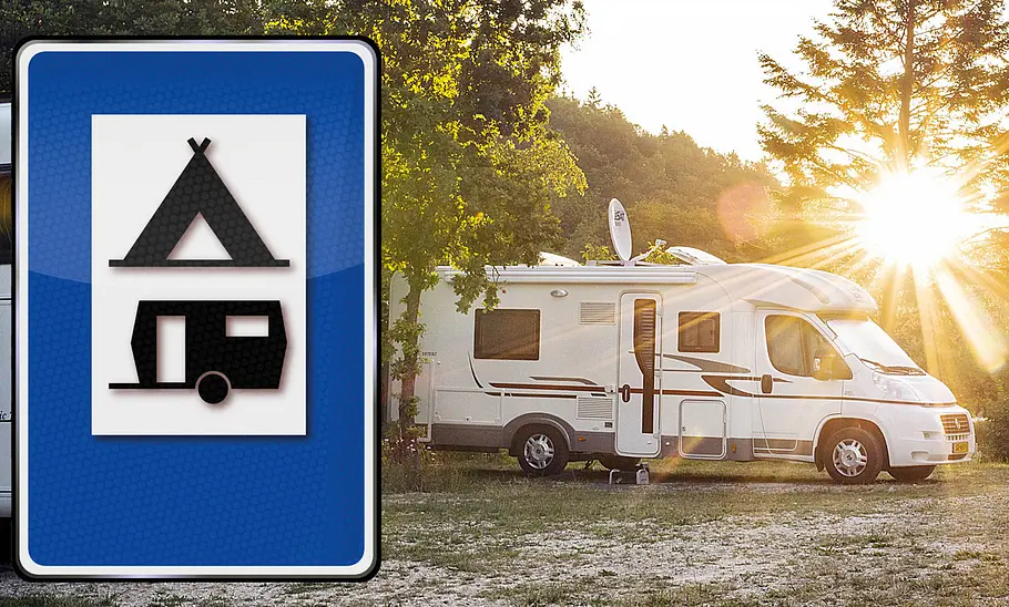 Das Bild zeigt ein Wohnmobil stehend von schräg vorne rechts fotografiert. Es steht auf einem Campingplatz zwischen Bäumen, im Hintergrund geht die Sonne unter.