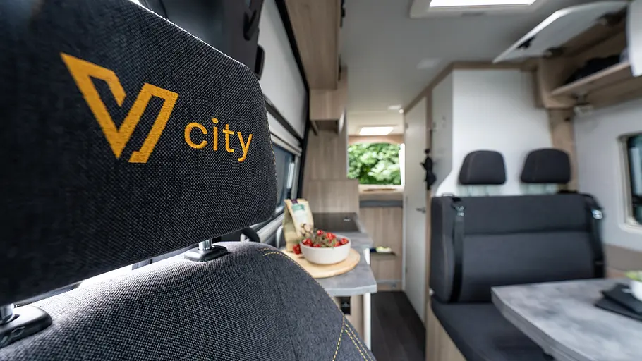 Yucon V-City Die mit dem Schriftzug V-City bestickte Kopfstütze des Beifahrersitzes im Yucon V-City im Detail.